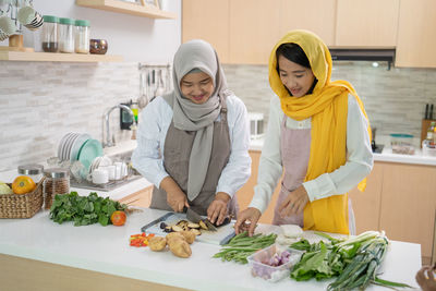 People standing by food in kitchen at home