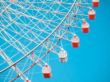 Low angle view of ferris wheel against clear blue sky