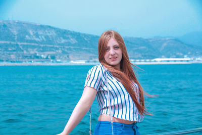 Portrait of young woman standing against sea