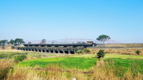 Abandoned train on field against clear blue sky