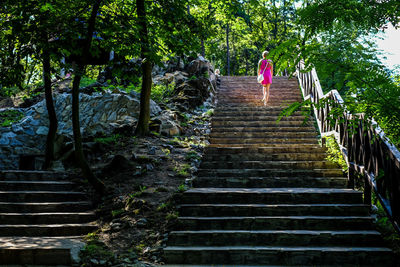 Rear view of woman walking on stairs in forest