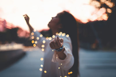 Close-up of hand holding illuminated lighting equipment at sunset
