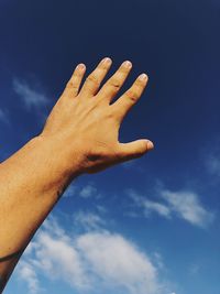 Low angle view of hand against blue sky