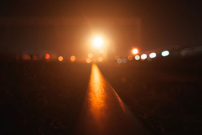 Illuminated city street against sky at night