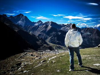 Rear view of man standing on mountain against sky