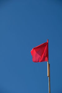 Low angle view of flag flags against clear blue sky