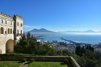 Scenic view of sea by buildings against clear blue sky