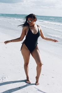 Full length of young woman standing on beach