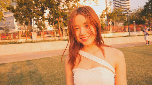 Portrait of smiling young woman standing against trees