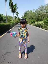 Girl wearing sunglasses on road against trees