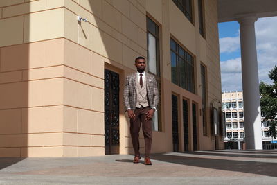 Portrait of young man standing against building