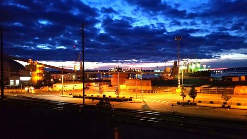 Illuminated road in city against sky at night