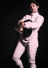 Portrait of young man standing against black background