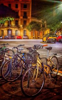 Bicycles parked against illuminated town in city