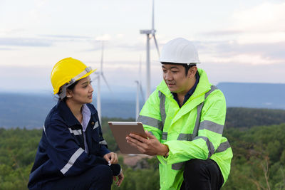 Engineers examining windmill through digital tablet