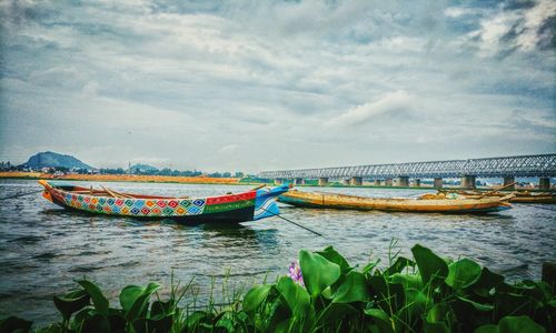 Boats moored in water against sky