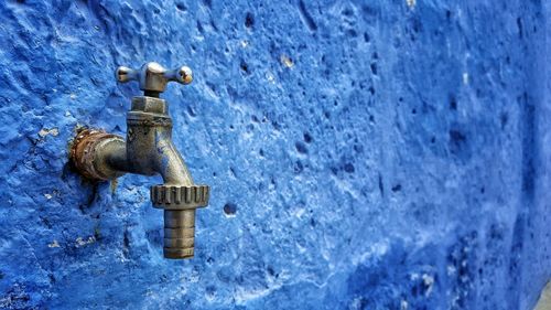 Close-up of faucet attached on blue wall