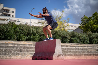 Woman jumping against built structure