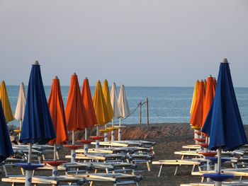 Panoramic view of deck chairs on beach against clear sky