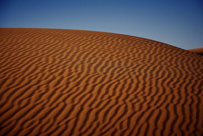 Sand dune in desert against clear sky