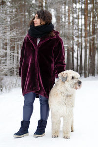 Full length of woman with dog standing on snow covered land