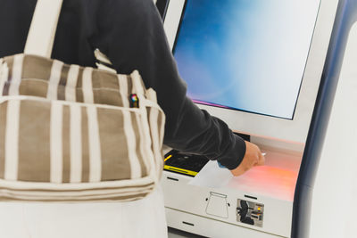 Woman passenger doing self check in scanning boarding pass at airport.