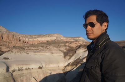 Young man wearing sunglasses standing against clear sky