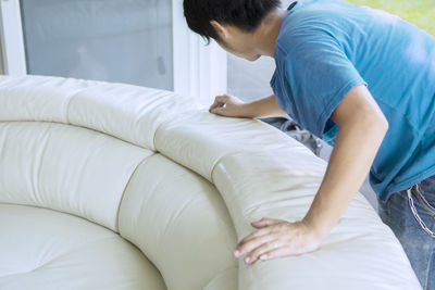 Side view of mature man adjusting sofa at home