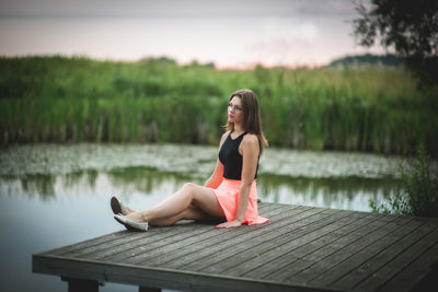 Woman sitting on pier over lake