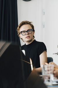 Young genderblend professional looking away while sitting in board room during meeting