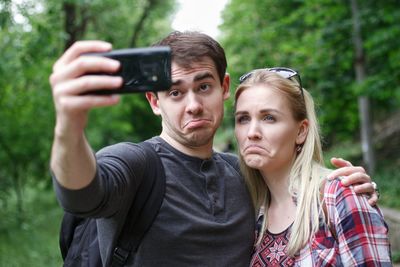 Friends taking selfie with smart phone at public park