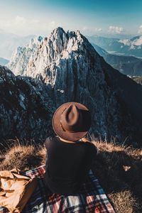 Rear view of man looking at snowcapped mountains against sky