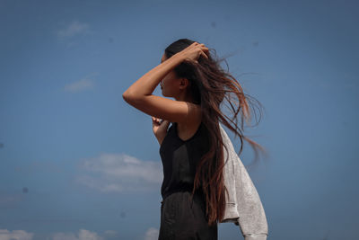 Low angle view of woman standing against sky