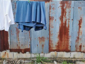 Clothes drying on rusty metal against wall