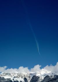 Low angle view of snowcapped mountains against blue sky