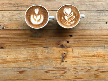 Cup of hot cappuccino coffee with beautiful latte art put on retro pattern wood table