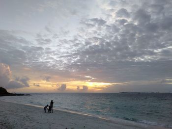 People on beach against sky during sunset