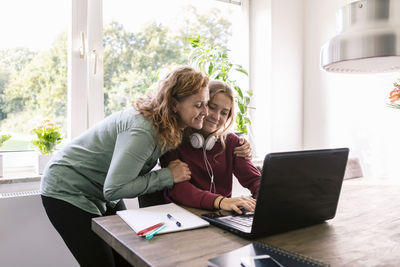 Smiling mother embracing daughter at home