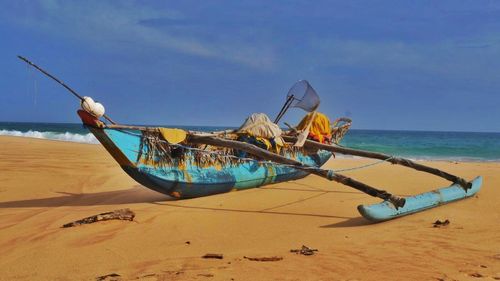 Old outrigger boat moored at sea shore on sunny day