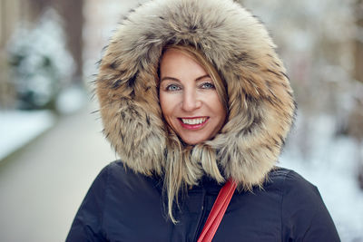 Portrait of smiling young woman wearing fur coat during winter