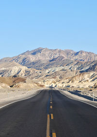 Road amidst mountains against clear sky