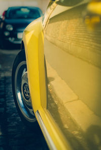 Close-up of yellow car on road