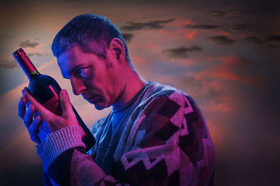 Close-up of man holding sunglasses against sky at night