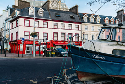 Boats moored in city against sky