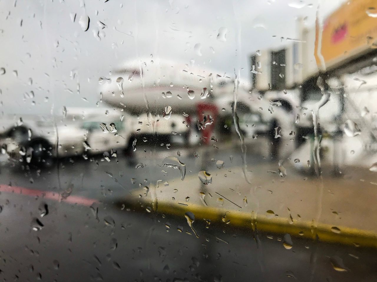 FULL FRAME SHOT OF WET GLASS WINDOW IN AIRPORT