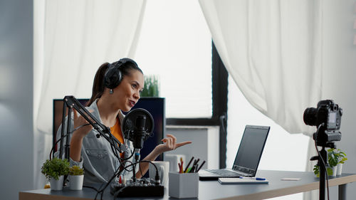 Side view of young woman using laptop at home