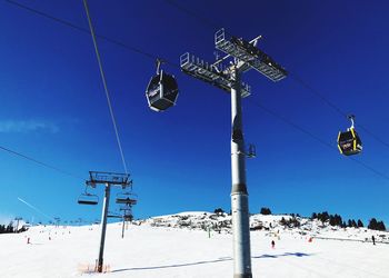 Low angle view of ski lift against blue sky