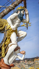 Low angle view of angel statue against buildings in city