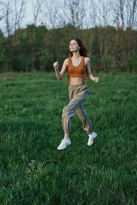 Full length of young woman exercising on field