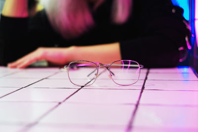 Midsection of woman with eyeglasses on table